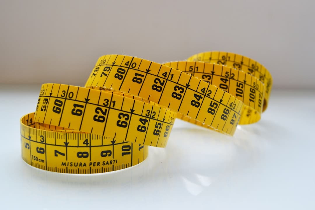 Lifter measuring upper arm with a fabric tape measure next to an open ForgeLogbook with measurement data