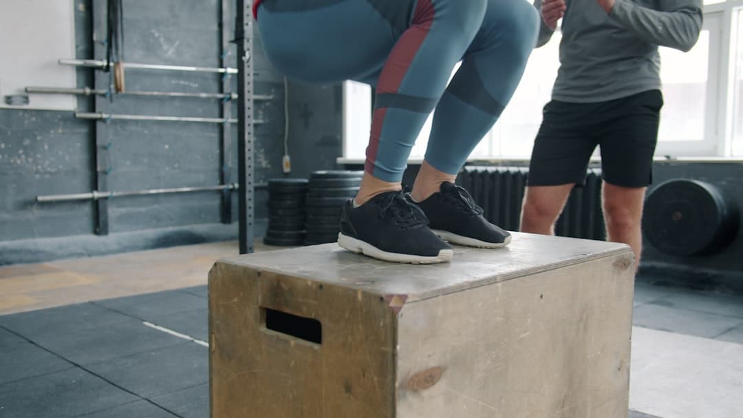 Stack of custom-branded gym logbooks on a CrossFit box with kettlebells in the background