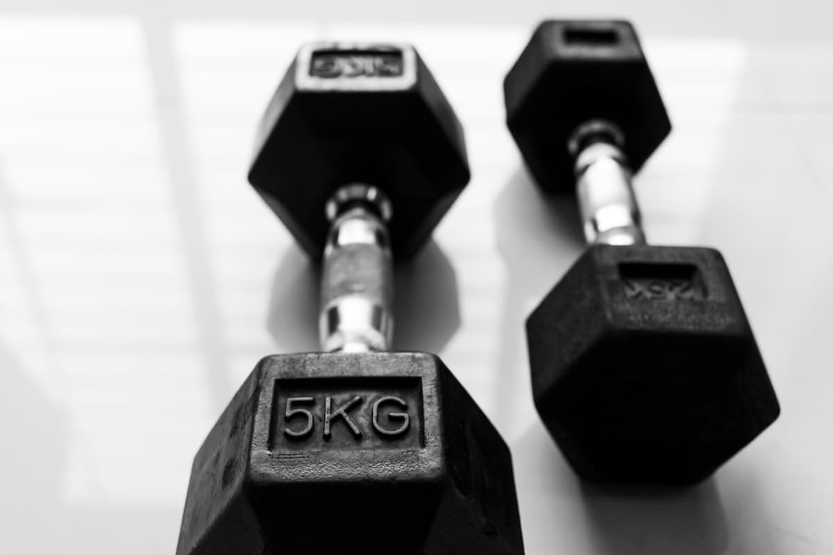 Lifter writing in a logbook between heavy barbell sets in a well-equipped power rack gym