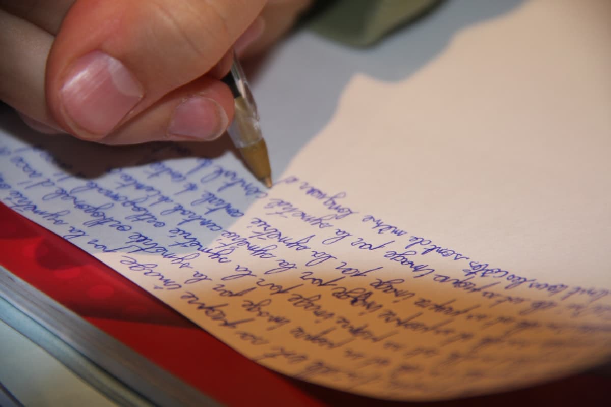 Close-up of a hand writing in a journal with warm lighting