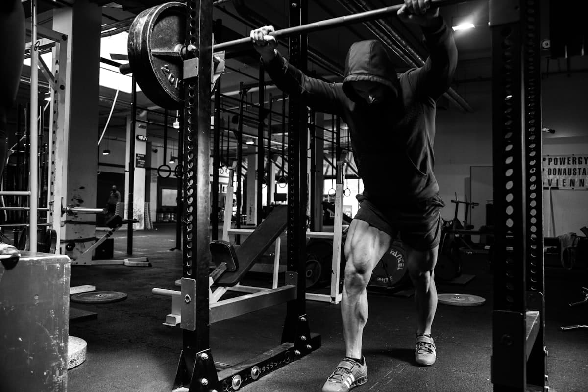 A weathered gym logbook sitting on a bench next to a barbell loaded with heavy plates, chalk dust visible on the pages