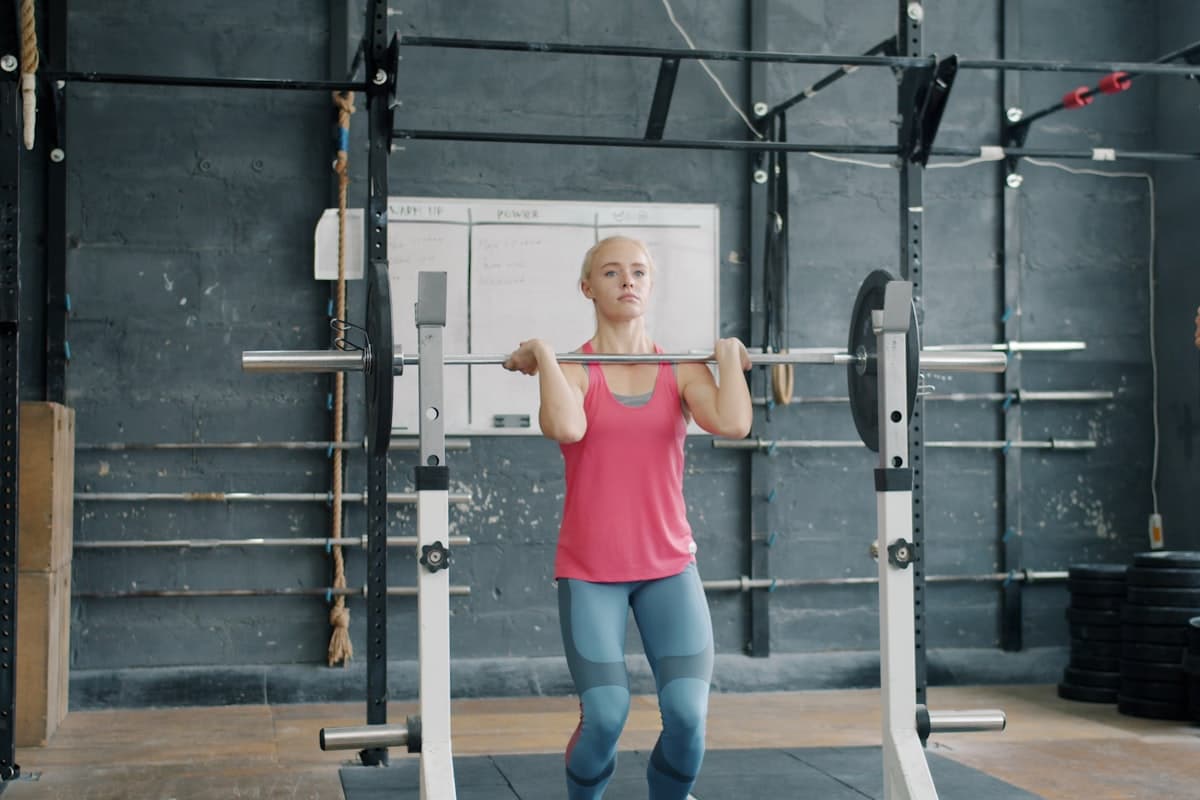Beginner lifter performing barbell squats in a clean gym setting
