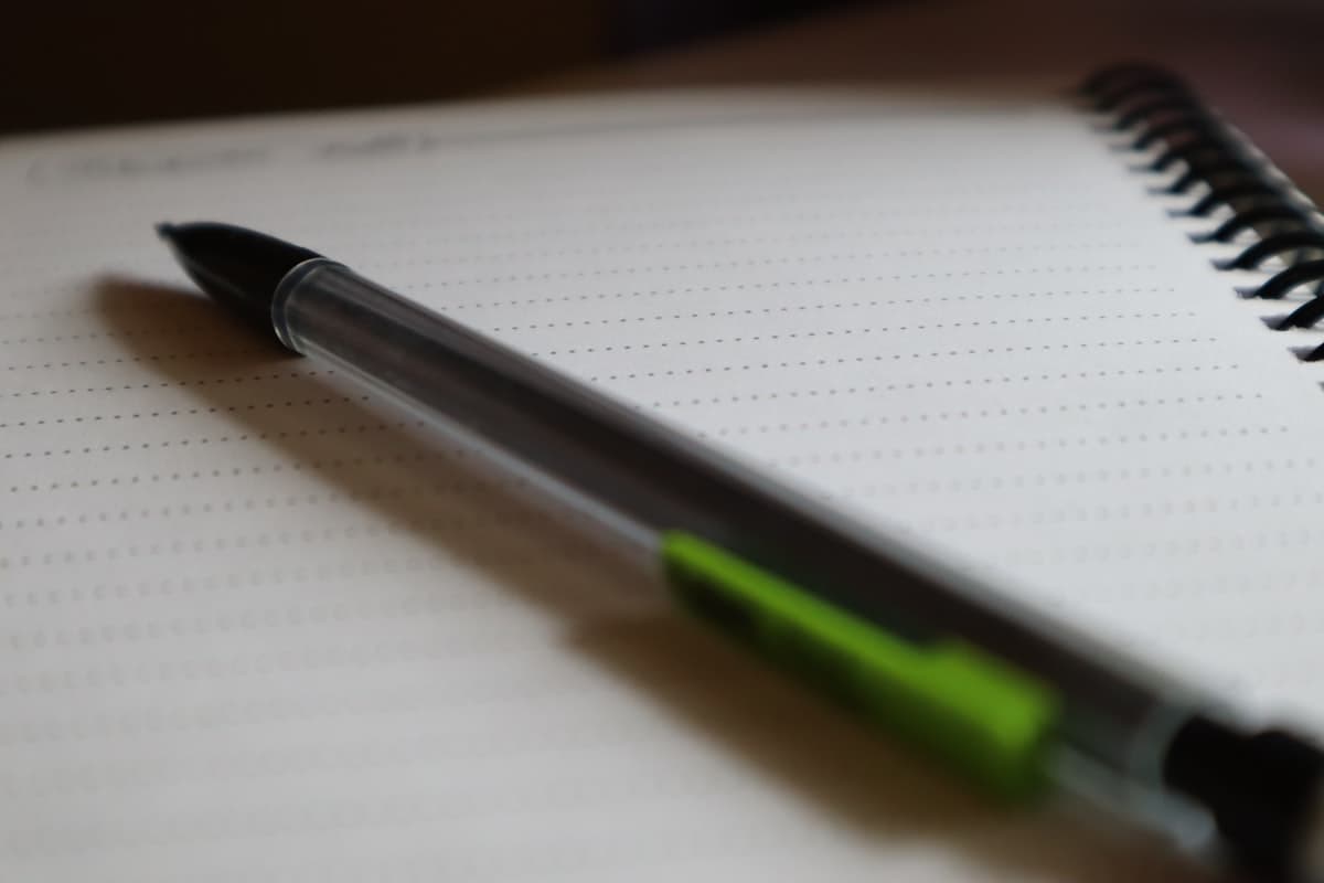 Close-up of a pen on lined notebook paper with structured handwriting